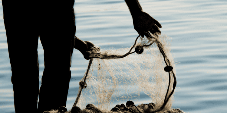 silhouette of man adjusting fishing net